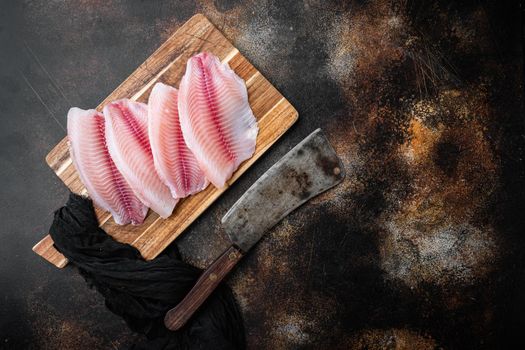 Raw tilapia fish fillet meat cuts, on old rustic background, top view with copy space for text