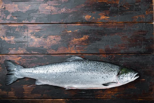 Whole raw salmon on wooden background, top view with space for text.