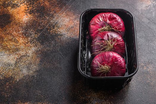 Farm red onions in tray on old oak wooden table. Side view space for text