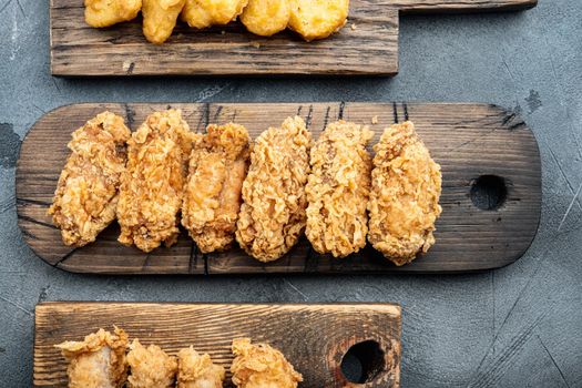 Fried chicken wings parts on grey background, flat lay.