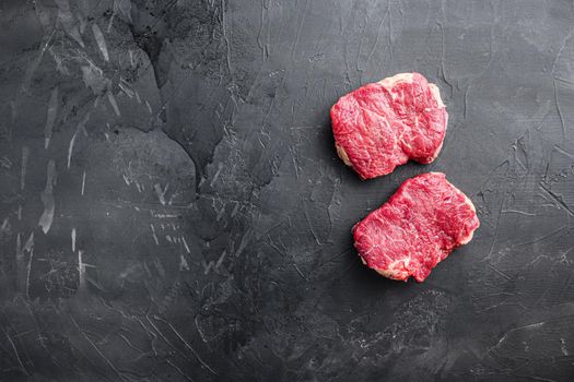 Raw rump steaks over black background, top view with space for text