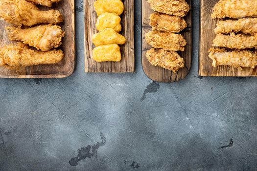 Homemade crispy fried chicken parts on grey background, top view, with copy space.