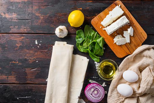 Greek spanakopita ingredients filo spinach eggs feta top view on dark wooden background space for text