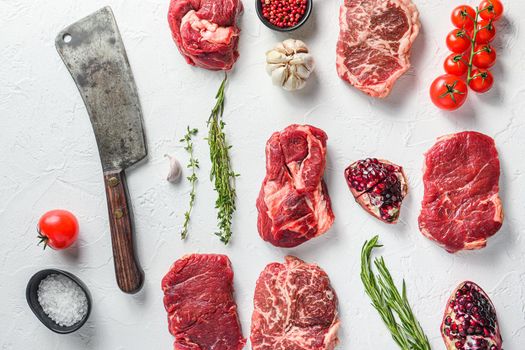 Beef cuts Chuck eye roll, top blade, rump steakwith herbs and pomegranate and butcher knife cleaver. Organic meat. White textured background. Top view
