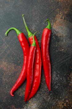 Ripe red chili peppers set, on old dark rustic background, top view or flat lay