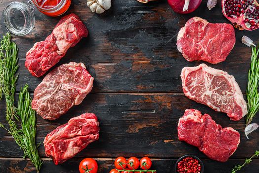 Meat beef steaks frame concept, with different steak cuts on dark old wooden table top view with space for text