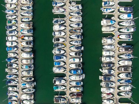 Aerial top view of boats and yachts in marina. Marina lot with yachts, sailboat and speedboat moored at the quay.