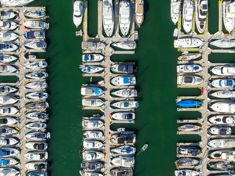 Aerial top view of boats and yachts in marina. Marina lot with yachts, sailboat and speedboat moored at the quay.