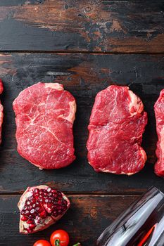 Set of raw beef rump steaks on old wooden dark planks top view with space for text