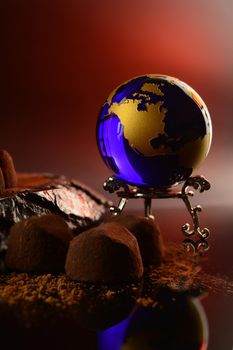 A globe of the Earth is in a scene of fine chocolate truffles.