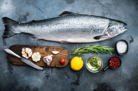 Whole raw salmon on grey background, flat lay.
