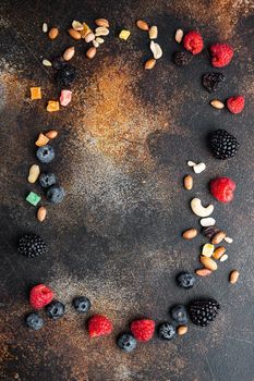 Frame made of mixed dried and raw ripe berry and fruit with nuts, top view with copy space, on old dark table