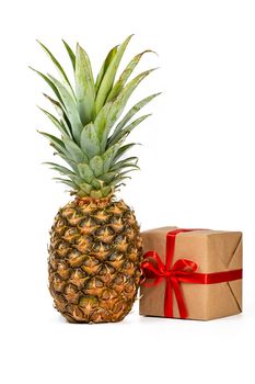 Fresh pineapple fruit and square gift box in craft paper isolated on white background