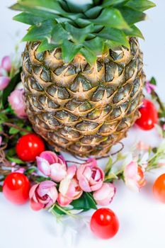 Easter composition of pineapple, flower wreath and colored eggs on white background