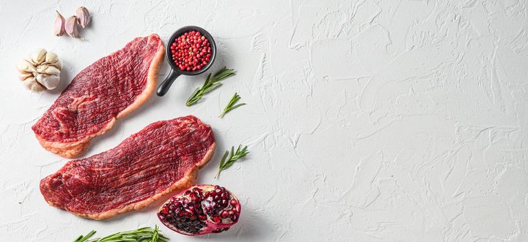 Couple picanha beef steak with rosemary and pomegranate top view over white textured background . Big size space for text