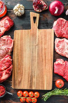 Meat beef steaks frame concept, with different steak cuts andempty chopping board in frame on dark old wooden table top view
