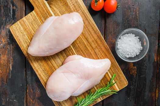 Raw meat, ready for grill or barbeque chicken breast filet, with herbs and spices on dark rusty wooden background, top view close up.