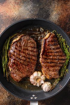 Grilled picanha organic beef steaks on pan with herbs and garlic. Over old dark metall background, top view