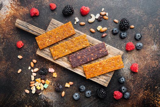 Healthy fitness energy bars with dried fruits and nuts, top view, on old dark table