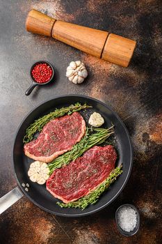 Picanha organic beef steaks ready for grill on pan with herbs and garlic. Over old dark metall background, top view