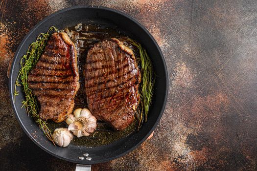 Grilled picanha organic beef steaks on pan with herbs and garlic. Over old dark metall background, top view with space for text