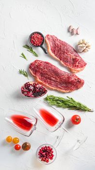 Picanha beef steak with glasses of red wine , rosemary and pomegranate top view over white textured background . Big size.