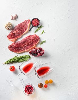 Raw picanha steak with glasses of red wine , herbs and pomegranate top view over white textured background . Big size