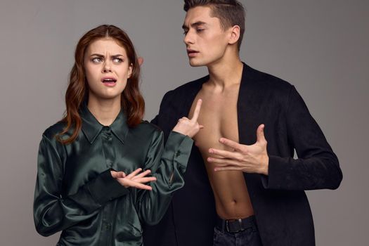 Conflict situation young people in suits on a gray background gestures with their hands problems in the family. High quality photo