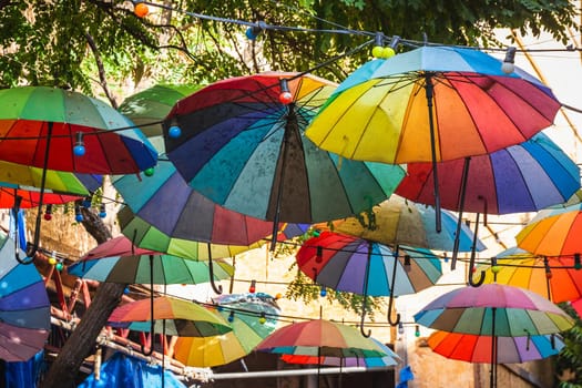 Multicolored umbrellas hang overhead in the street near Galata Tower.