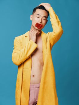 A half-naked man in a yellow jacket and pink trousers with a flower in his mouth. High quality photo