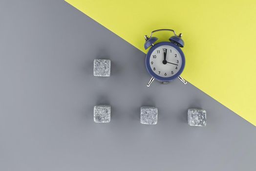 Alarm clock on a two tone grey and yellow background with copy space viewed as a flat lay. Renovation and color trends concept