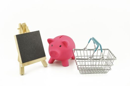 Pink pig saver, small chalk board and wire shopping basket isolated on a white background