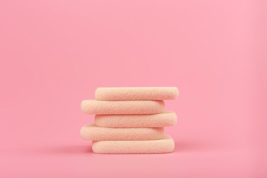 Horizontal minimalistic still life with stack of beige make up sponges on pink background with copy space. High quality photo