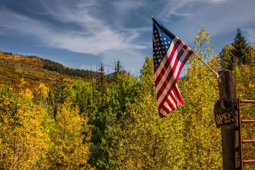 American flag with beautiful yellow autumn aspen tree leaves at the background. Taken in Black Hawk city turned into gambling destination of Colorado Rocky Mountains, USA.