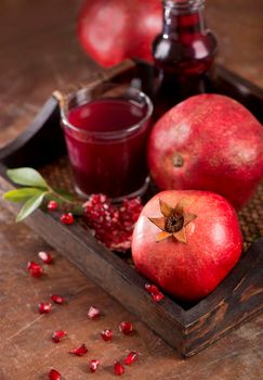 Glass of pomegranate juice and pomegranate fruit on wooden background