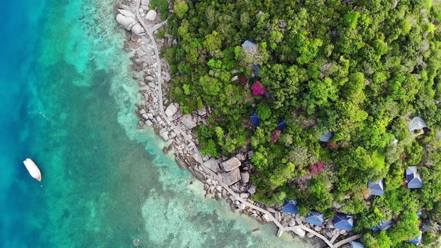 Calm colorful azure turquoise sea near tiny tropical volcanic island Koh Tao, unique small paradise Nang Yuan. Drone view of peaceful water near stony shore and green jungle on sunny day in Thailand