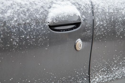 dry dirty and snowy black car door with keyhole of mechanical lock.
