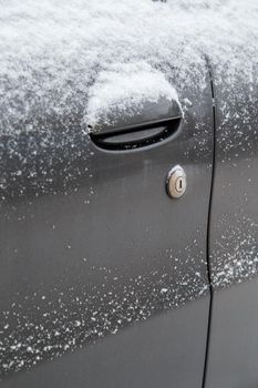 dry dirty and snowy black car door with keyhole of mechanical lock.