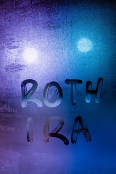 the words roth ira - individual retirement account handwritten on night wet window glass surface.