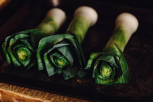 Fresh green leek stalks on metal tray