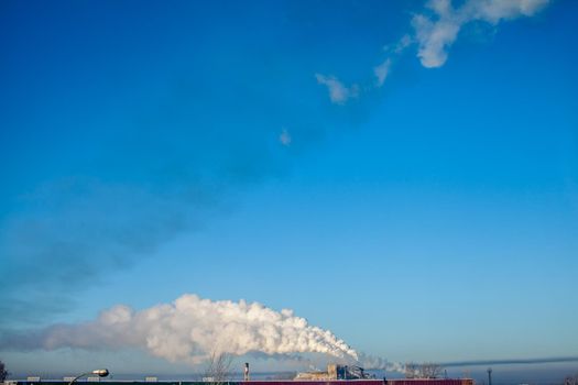 White thick smoke from the boiler room chimney. Smoke against the blue sky. Air pollution. Heating of the city. Industrial zone.