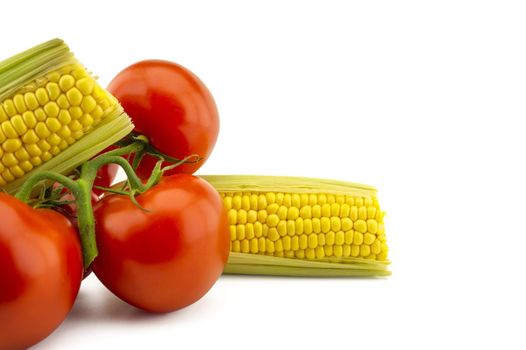 Juicy ripe red tomato and fresh corncob over white background