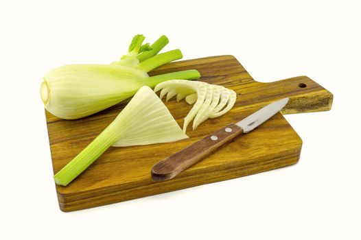 Preparing fresh fennel slicing them on a wooden cutting board over a white background in a healthy diet and nutrition concept