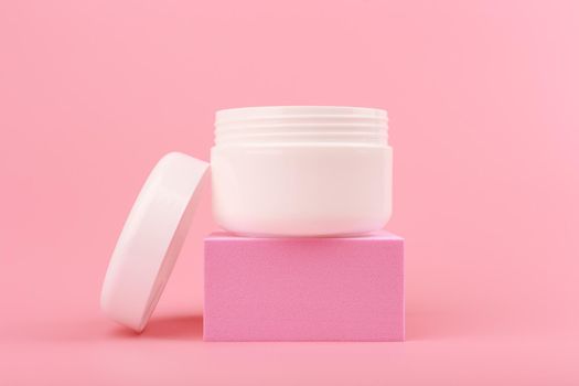 Close up with face cream. mask or balm in white jar with opened cap on pink podium against pink background. High quality photo