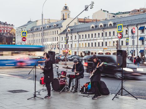 MOSCOW, RUSSIA - November 14, 2020. Street musicians play in the town square. Youth rock band on background of evening lights of capital.
