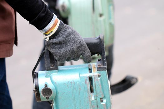 Male workers use electric concrete breaker for digging and drilling concrete repairing driveway surface with jackhammer at the local city road, during sidewalk, work construction site.