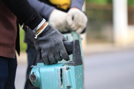 Male workers use electric concrete breaker for digging and drilling concrete repairing driveway surface with jackhammer at the local city road, during sidewalk, work construction site.