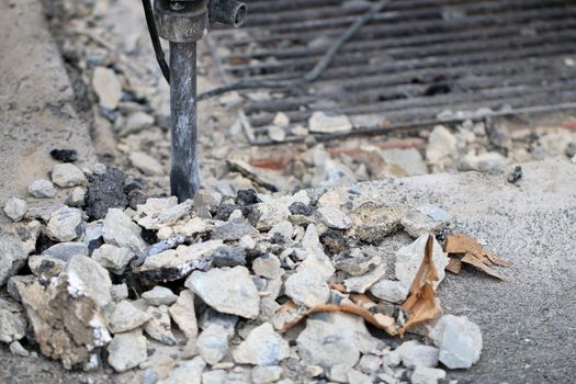 Male workers use electric concrete breaker for digging and drilling concrete repairing driveway surface with jackhammer at the local city road, during sidewalk, work construction site.