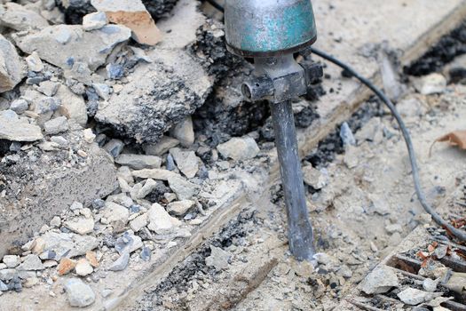 Male workers use electric concrete breaker for digging and drilling concrete repairing driveway surface with jackhammer at the local city road, during sidewalk, work construction site.