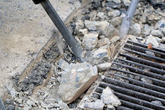 Male workers use electric concrete breaker for digging and drilling concrete repairing driveway surface with jackhammer at the local city road, during sidewalk, work construction site.